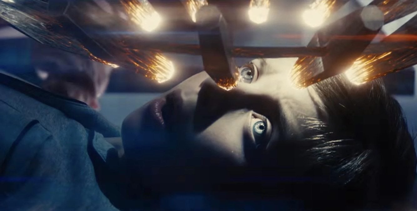Cena de Dia D com Emily Blunt em redação caótica, telões exibindo sinais e notícias sobre atividade alienígena