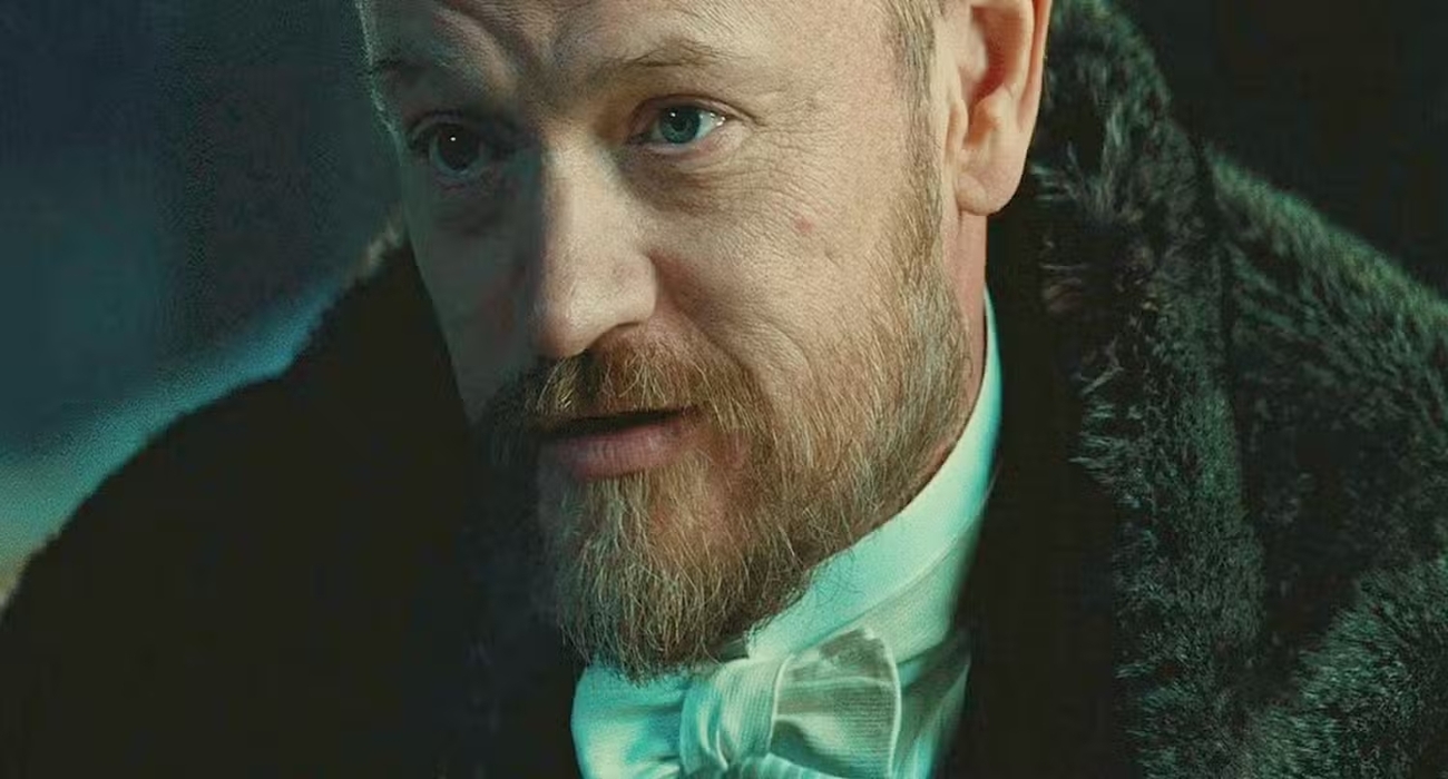 Moriarty e a detetive Imogen Burrows lado a lado em uma delegacia britânica moderna, clima de thriller policial