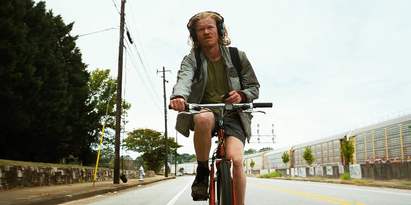 Teddy (Jesse Plemons) andando de bicicleta com fones de ouvido em Bugonia