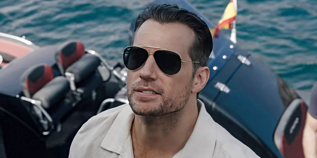 Henry Cavill em cena de ação de Na Zona Cinzenta, com traje tático e ambiente urbano noturno