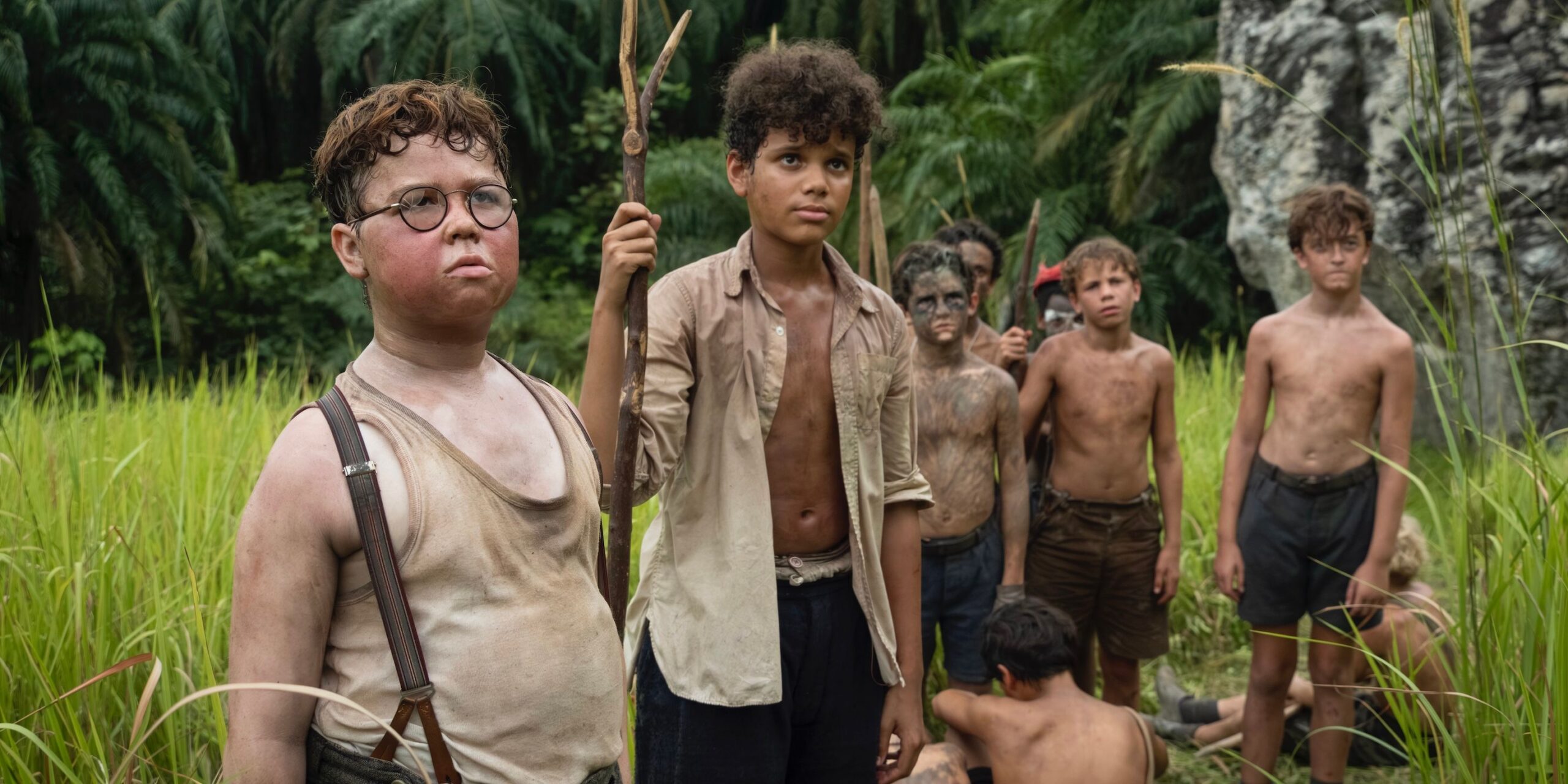 Grupo de meninos em conversa em ilha tropical, dois personagens em primeiro plano olhando para o lado