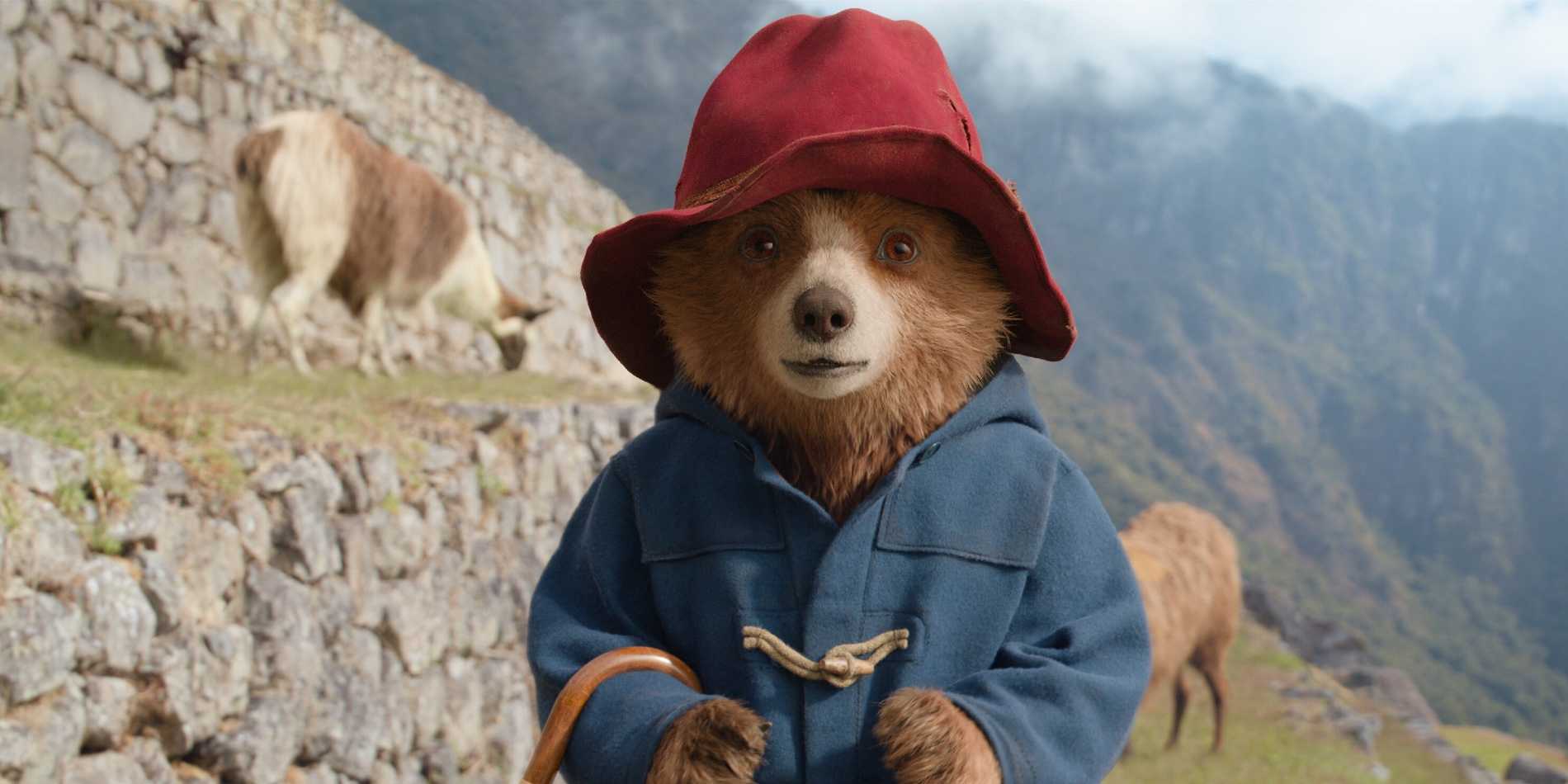 Paddington Bear, vestindo um casaco azul e chapéu vermelho, está em uma montanha em Paddington no Peru