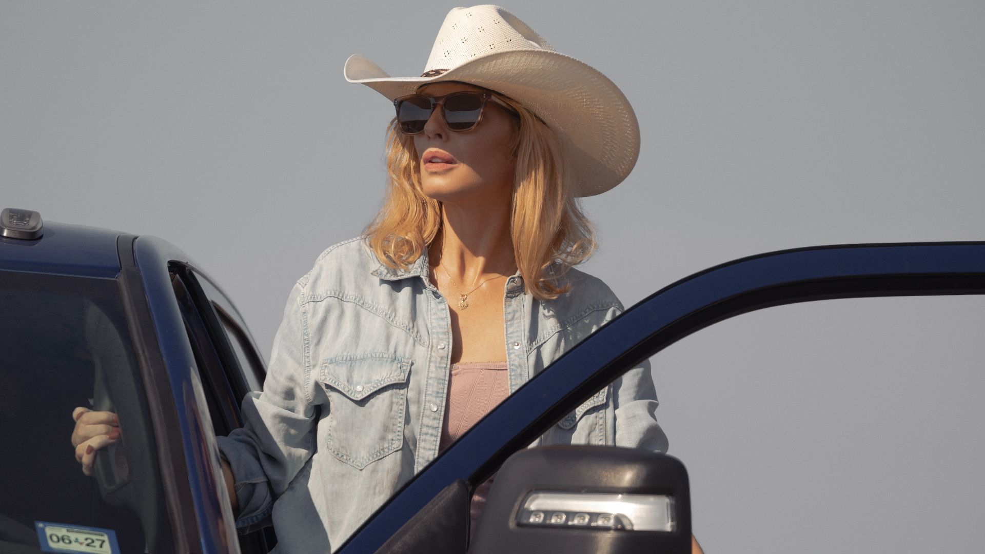 Beth Dutton com óculos de sol em cena externa do spin-off no Texas