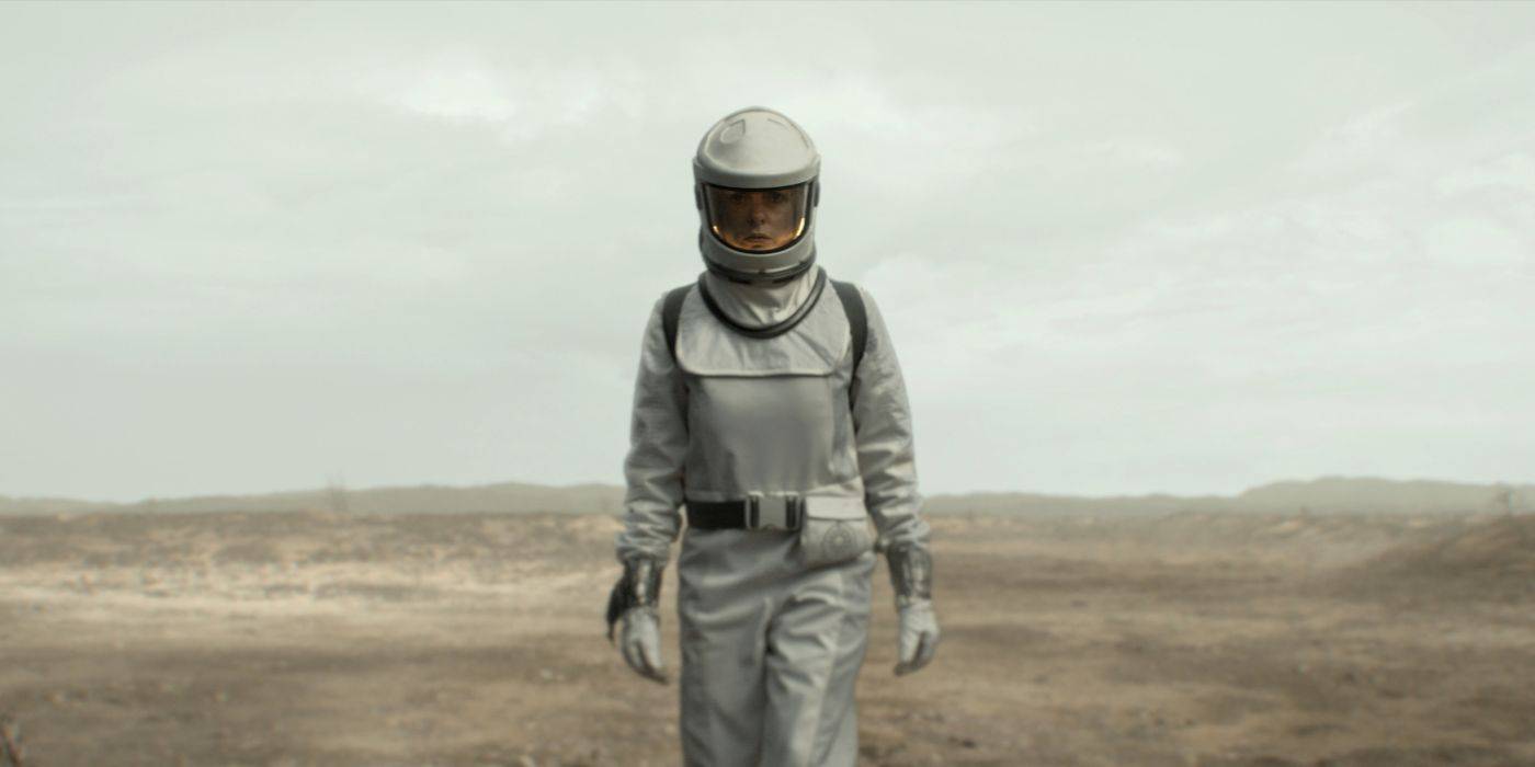 Juliette, interpretada por Rebecca Ferguson, caminha em direção à câmera pelo deserto usando um traje espacial em Silo.