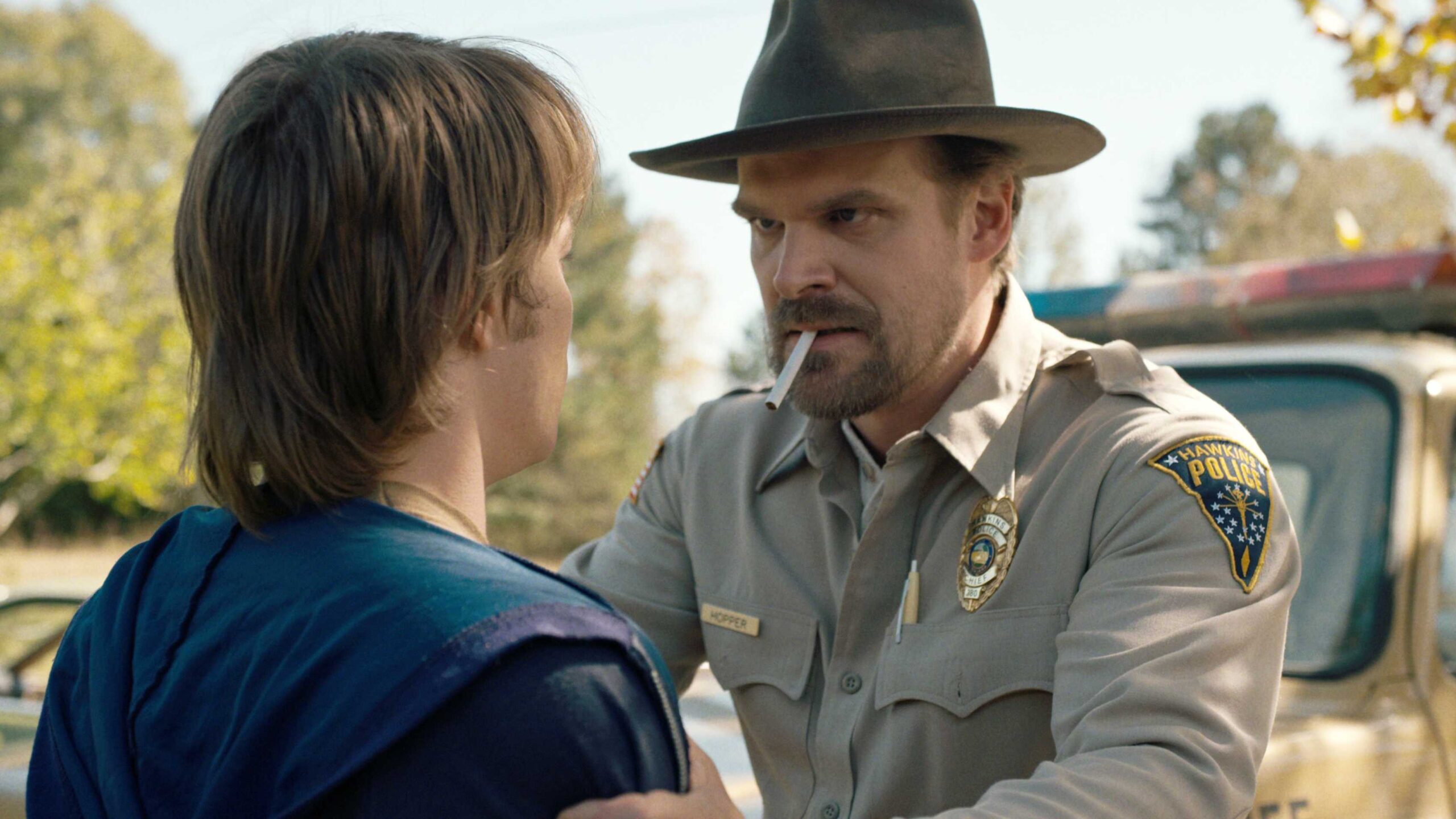 Jim Hopper (David Harbour) segurando os ombros de Jonathan (Charlie Heaton) em Stranger Things temporada 1