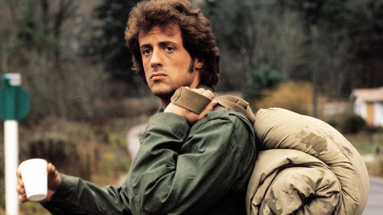 Sylvester Stallone segurando um copo como John Rambo