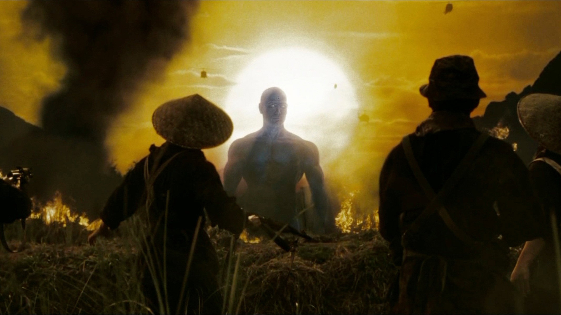 Super-herói azul gigante caminhando em campo dourado cercado por silhuetas de soldados com chapéus cônicos sob sol amarelo intenso