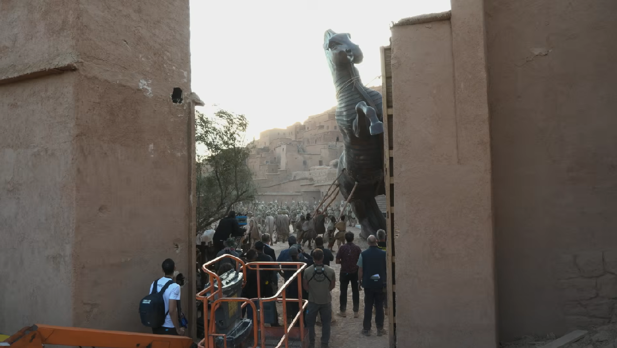 Matt Damon e Tom Holland em set externo de A Odisseia, com figurinos épicos e terreno rochoso ao redor