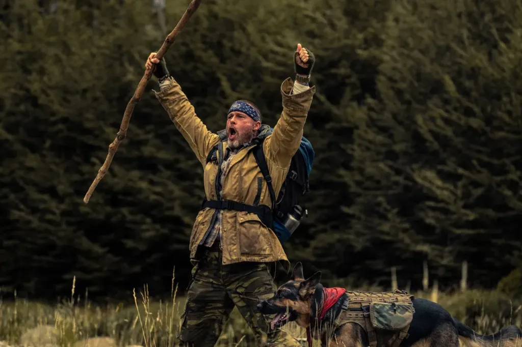 Cena do protagonista ao lado do cão de combate aposentado em paisagem gelada do Alasca, destaque para a relação entre os dois