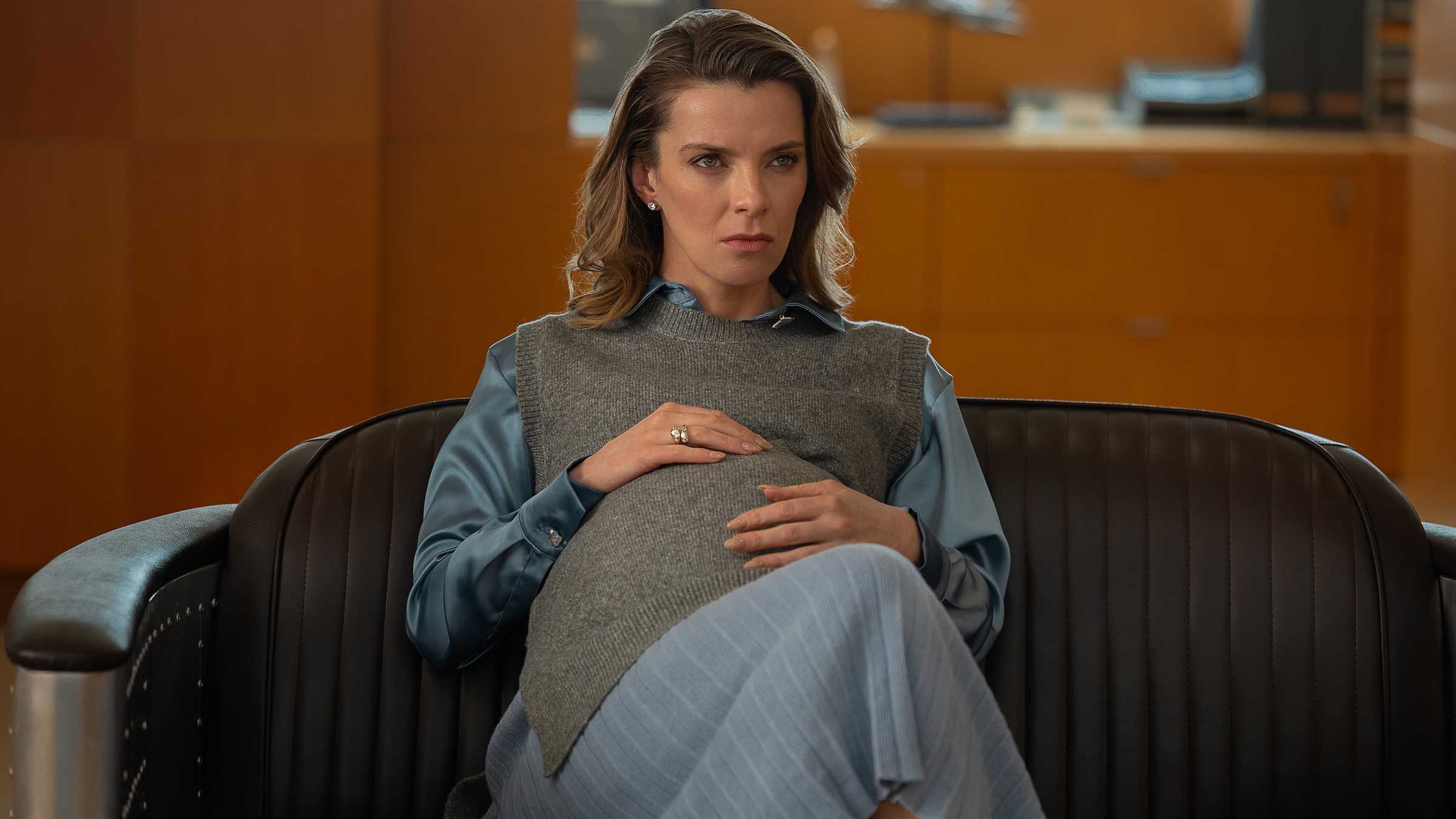 Sydney de Betty Gilpin olhando intensamente enquanto está sentada com a mão na barriga grávida em Office Romance