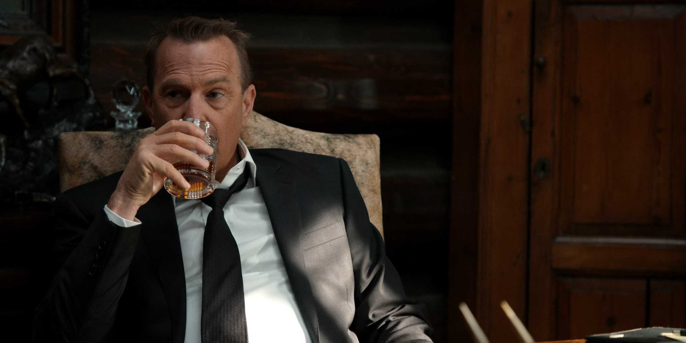 Kevin Costner como John Dutton vestindo terno e tomando uma bebida em Yellowstone Temporada 3 Episódio 1