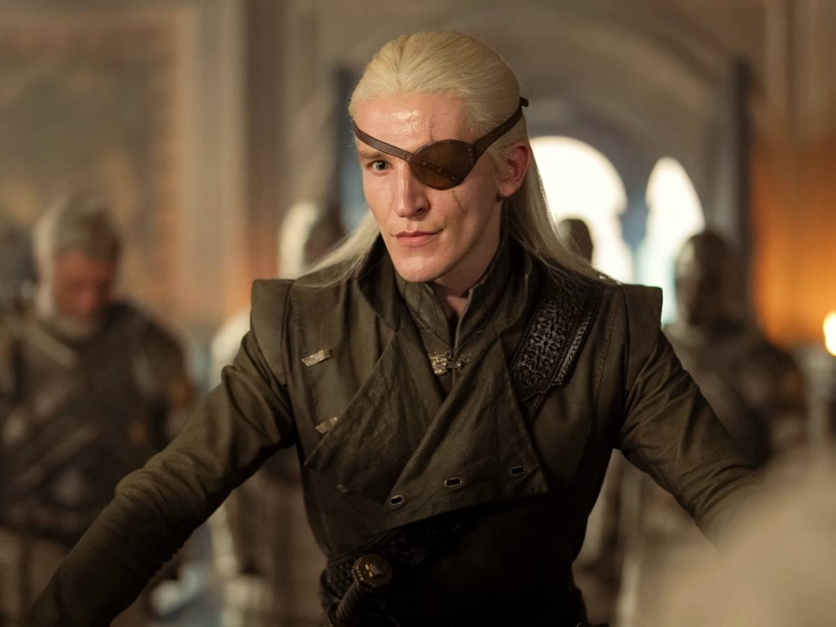 Aemond Targaryen montado em Vhagar sobre um campo de batalha escuro, com expressão fria e tensa