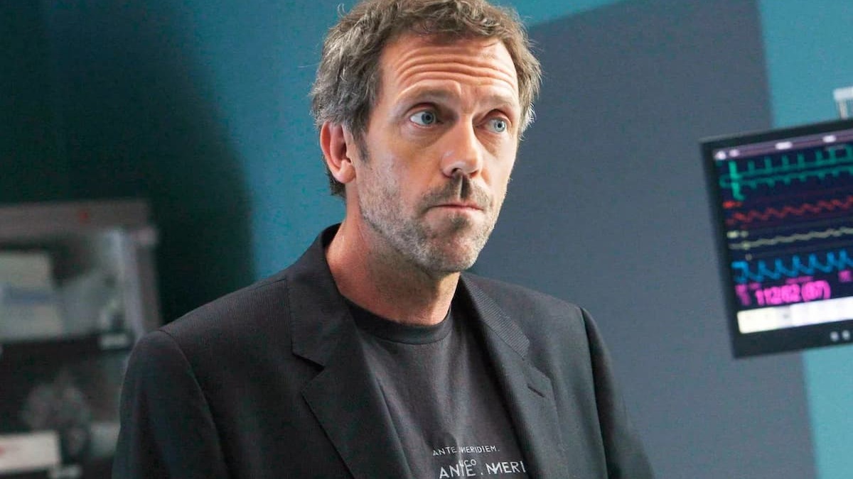 Tela de hospital de House com quadro de diagnósticos e equipe médica discutindo o caso
