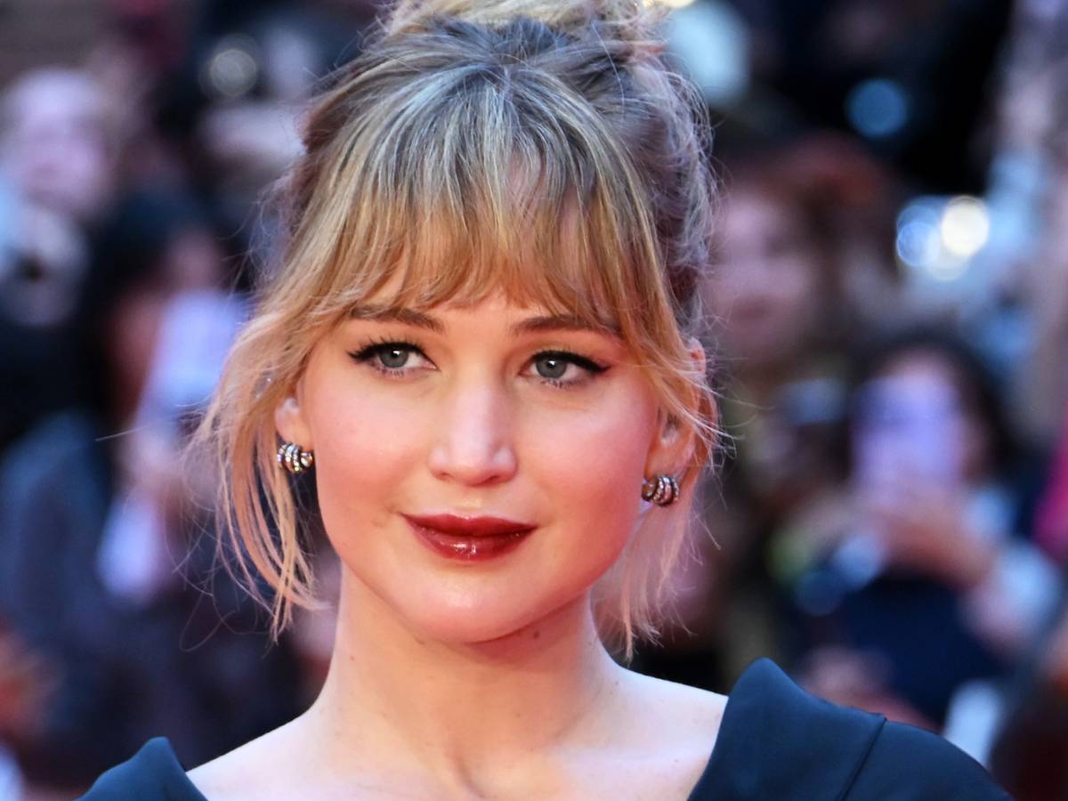 Interior luxuoso da nave Avalon em Passageiros, com Jennifer Lawrence observando o espaço pela janela