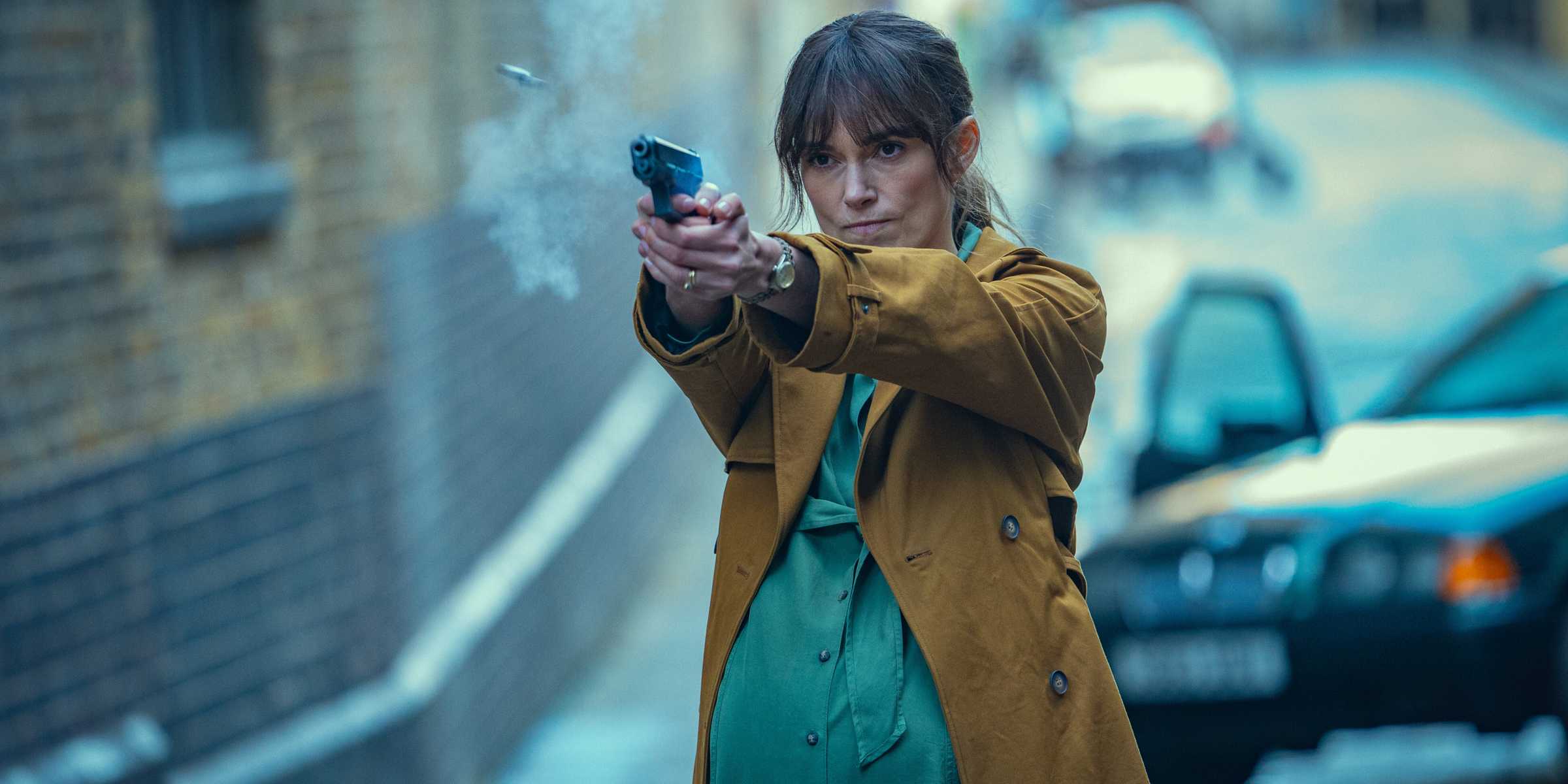 Keira Knightley como Helen disparando uma pistola na frente de um carro em Black Doves temporada 1