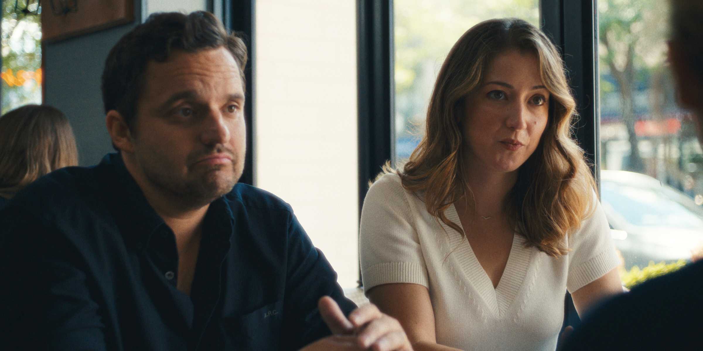 Jake Johnson e Jessy Hodges sentados um ao lado do outro e conversando com alguém em um restaurante em Maximum Pleasure Guaranteed
