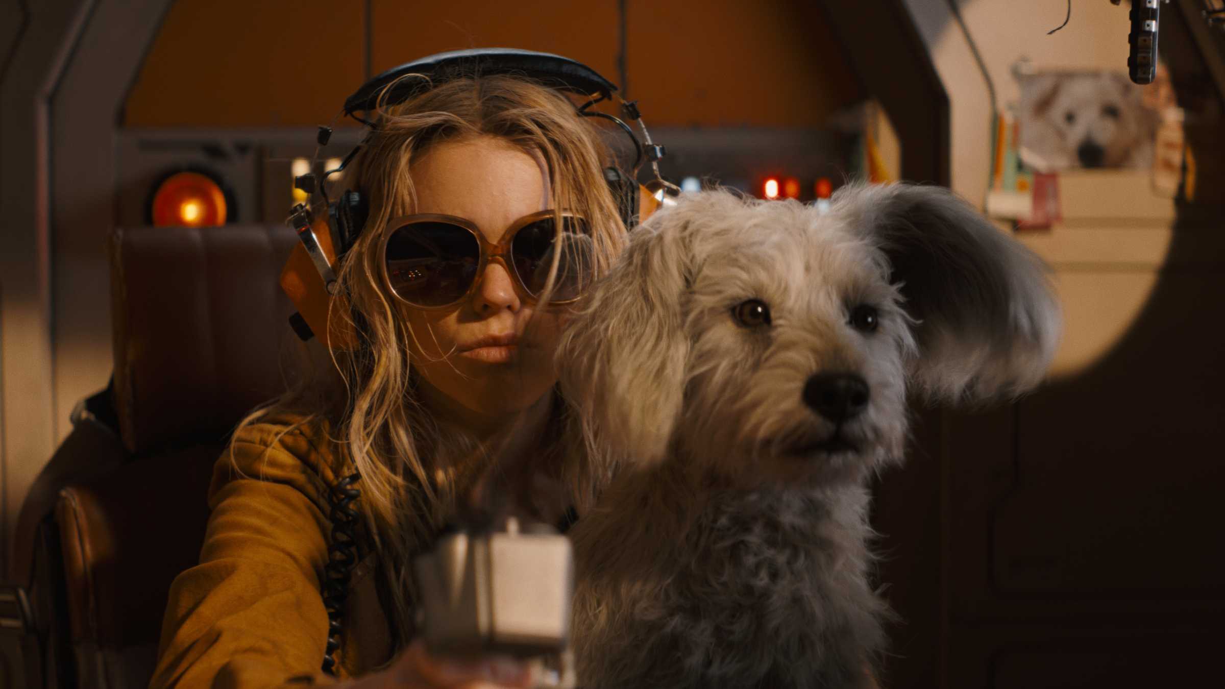 Milly Alcock como Supergirl dirigindo sua nave espacial com Krypto no colo em Supergirl