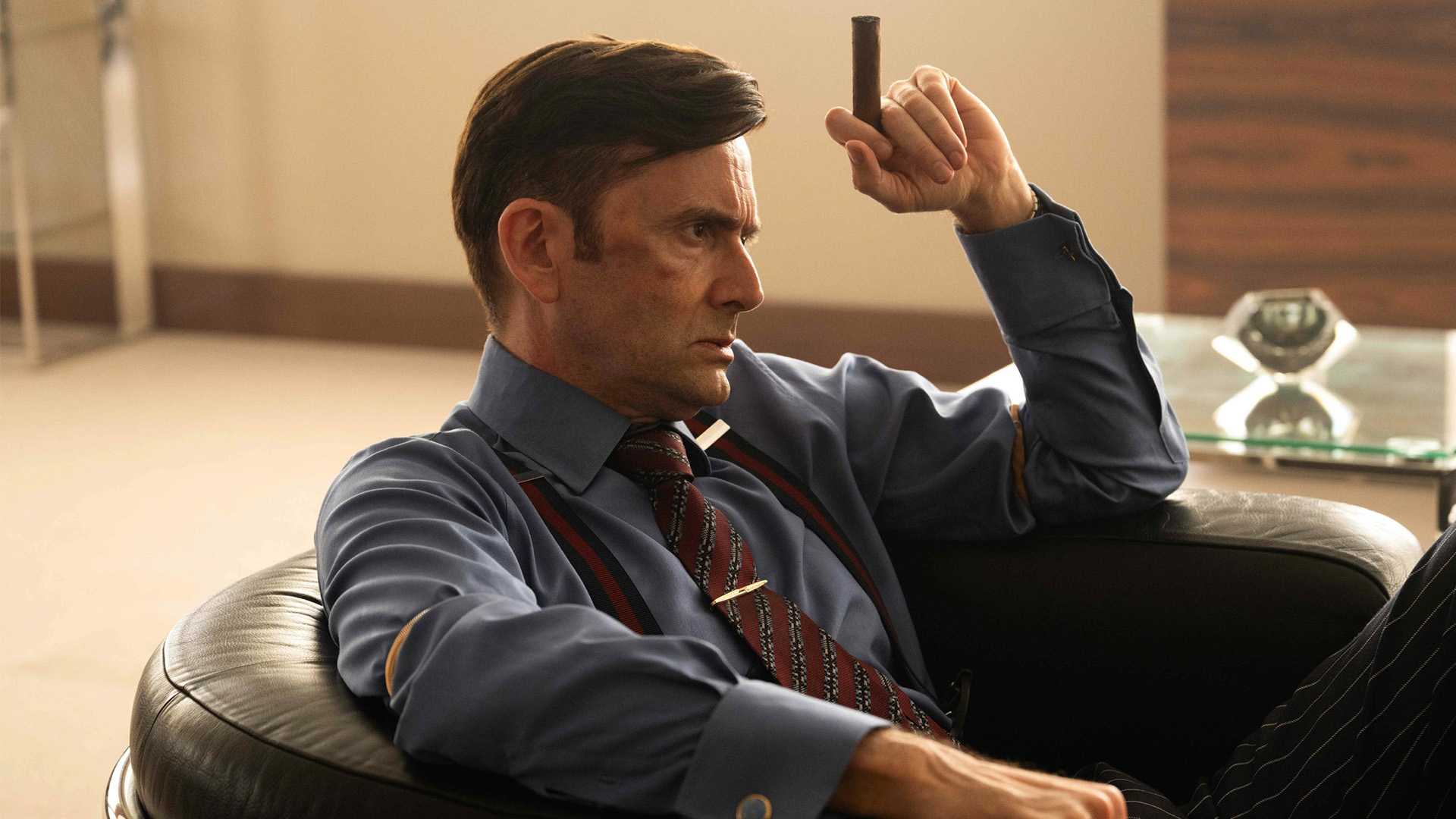 David Tennant segurando um charuto em Rivals temporada 2