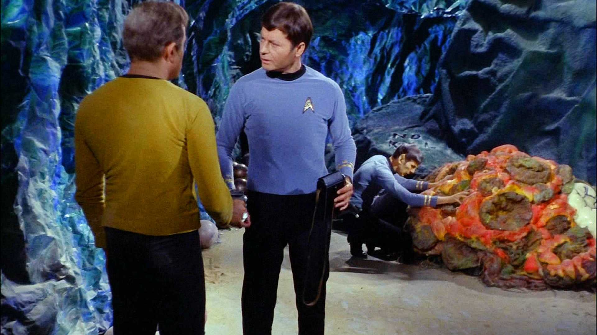 Spock se funde com a Horta ao fundo enquanto McCoy conversa com Kirk (dublê de Shatner de costas para a câmera) em Star Trek The Original Series