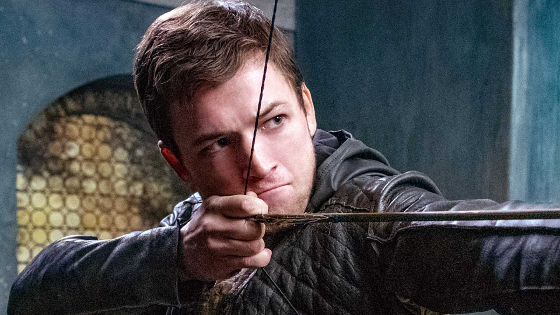Taron Egerton mira seu arco e flecha em Robin Hood 2018