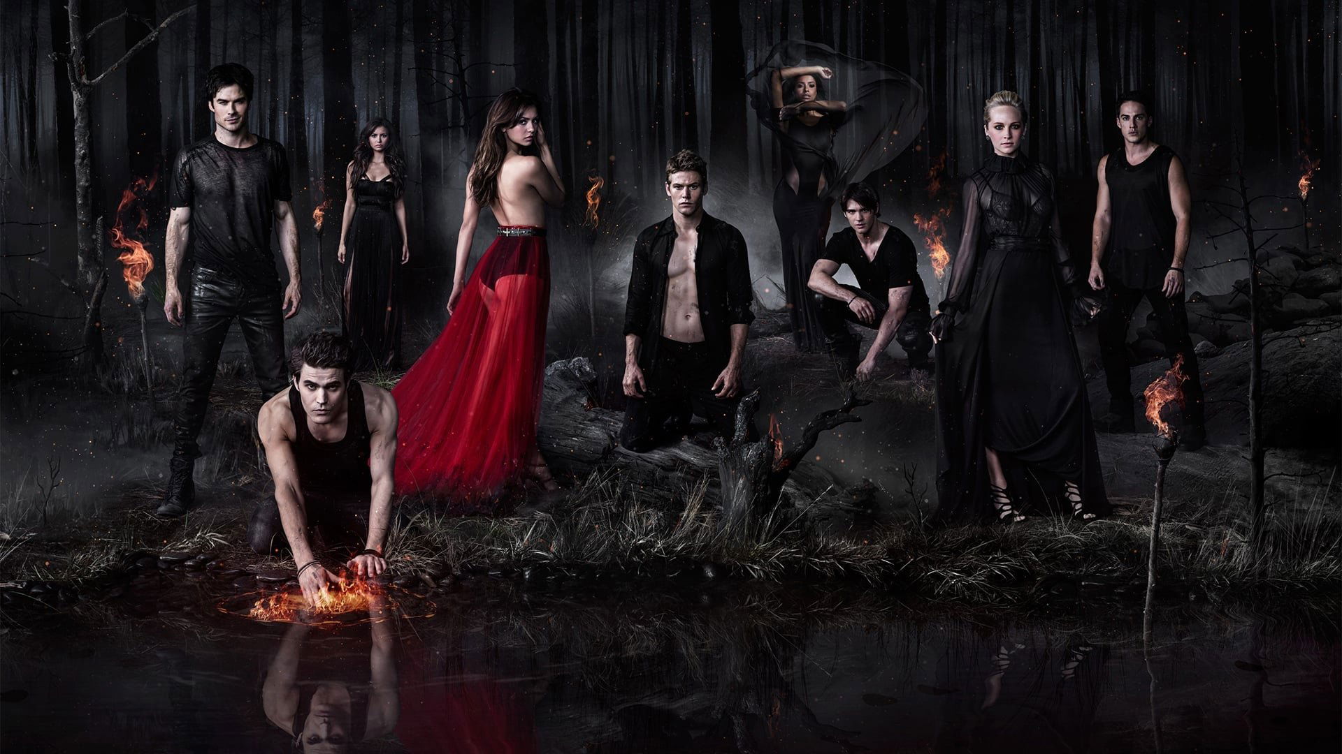 Grupo de personagens em floresta escura com chamas de fogo vermelho-alaranjado ao redor, cena noturna sobrenatural