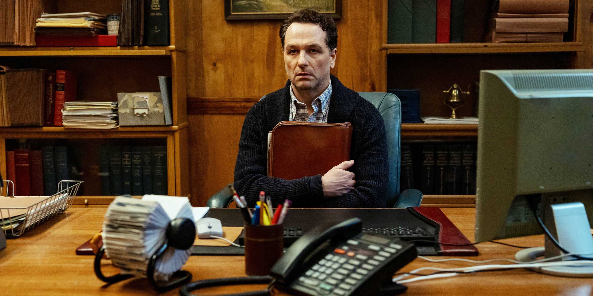 Matthew Rhys segurando uma bolsa e olhando fixamente à frente em Widow's Bay