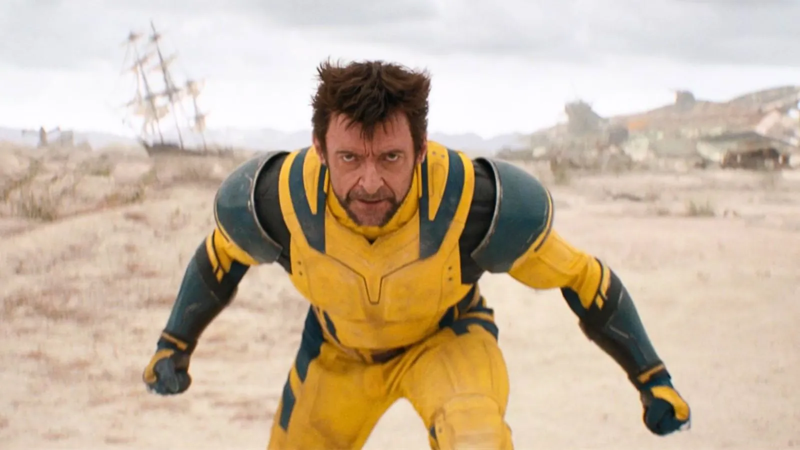 Hugh Jackman em evento da Marvel no tapete vermelho, cercado por fotógrafos e logo de Wolverine ao fundo